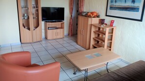 A living room with a TV, wooden cabinets, a sofa, and a table. - Apartment in Leudersdorf, Eifel With Terrace (Üxheim)