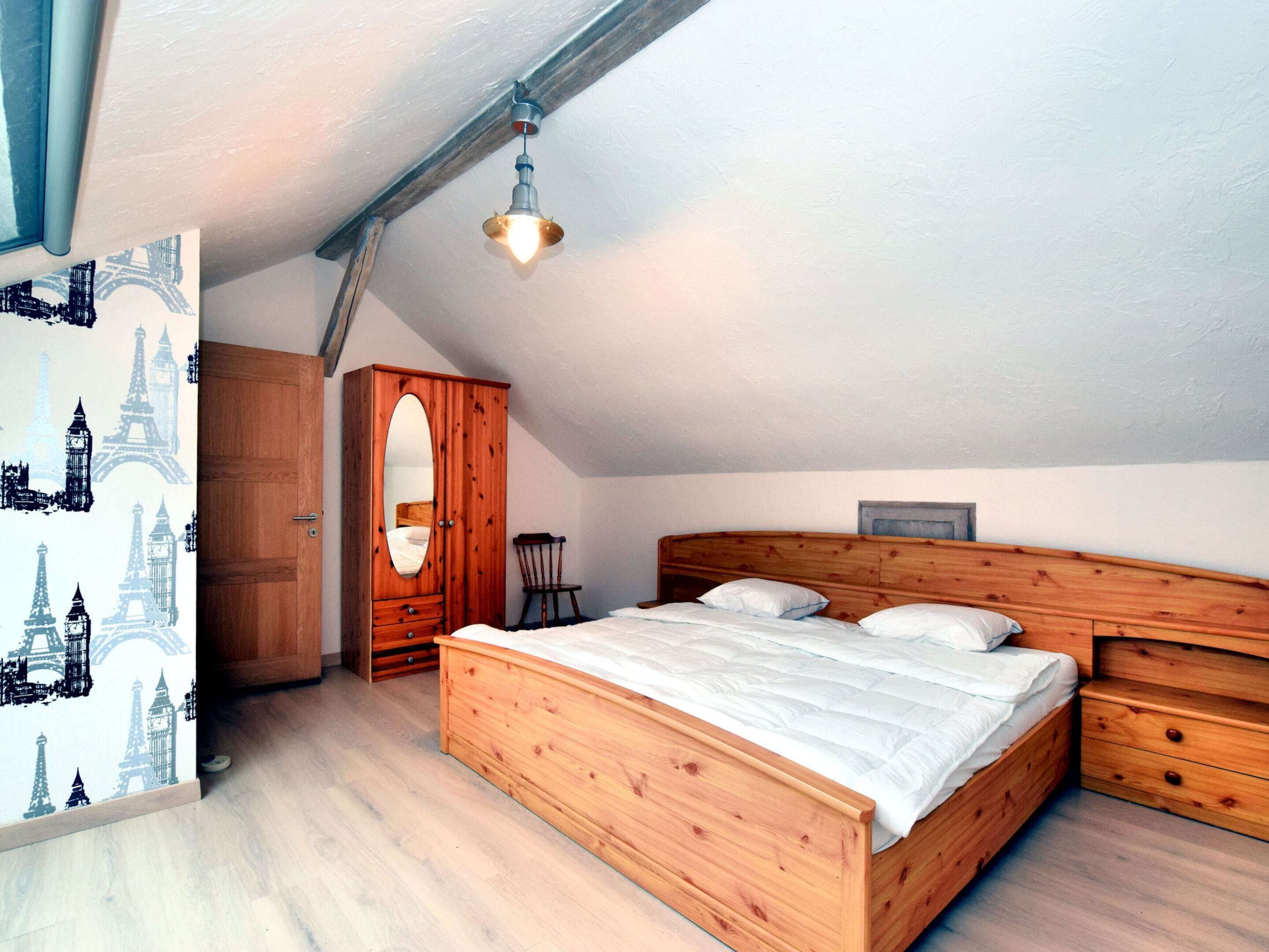 Una camera da letto con un letto e un armadio in legno, una sedia e un lampadario.