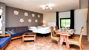 Ein Zimmer mit einem Bett, einer Couch, einem Esstisch mit Stühlen und Wanddekoration.
