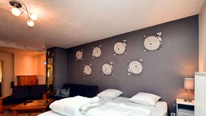 Ein Hotelzimmer mit einem großen Bett, zwei Nachttischen, einem Sofa und einer Wand mit dekorativen Blumenmustern.