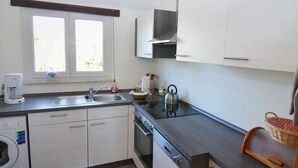 A modern kitchen with white cabinets, a stainless steel kettle, and a coffee maker. - Apartment in the Middle of Franconian Switzerland (Kunreuth)