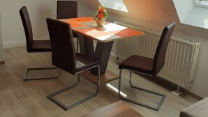 Ett modernt matområde med ett bord och stolar, en blomvas och utsikt genom ett takfönster.