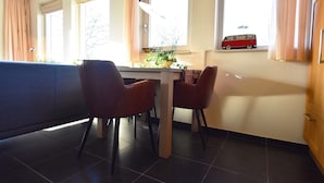 A dining area with a table and chairs, a window with a toy van, and a radiator. - Rural Holiday Home With Terrace (Zuidwolde)