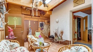 A cozy room with wicker furniture, a wooden ceiling, and a rustic decor including antlers and a stuffed animal.
