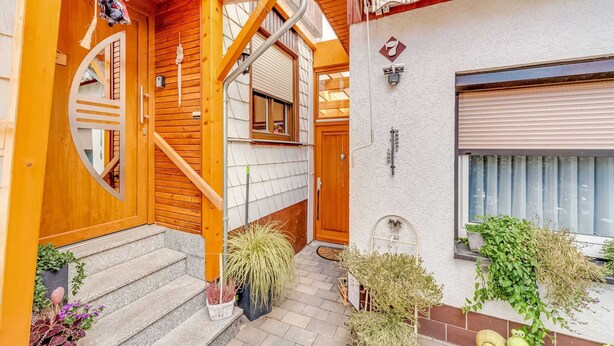 A wooden exterior with a spiral staircase, a small porch area, and potted plants.