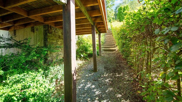 A covered wooden structure with a stone wall and a gravel path leading to a staircase. - Forest-edge Hideaway, Bouillon (Bouillon)