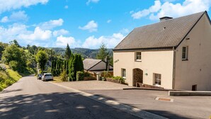 A two-story building with a stone facade, a sloped roof, and a driveway leading to a parking area. - Forest-edge Hideaway, Bouillon (Bouillon)