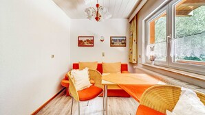 A room with a bed, a table, and two chairs. There are two framed pictures on the wall. - Rustic Black Forest Getaway (Masserberg)