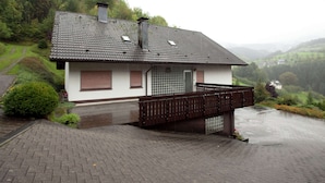 A two-story house with a sloped roof, a small balcony, and a paved driveway. - Apartment With Garden (Bad Peterstal-Griesbach)