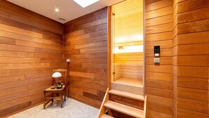 Una sala de sauna con paneles de madera, un banco de madera, una lámpara y una puerta de cristal que da a una zona de ducha.