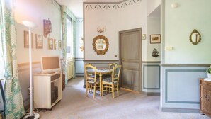 A dining area with a table and chairs, a television on a stand, and framed pictures on the wall. - Villa in Grimaud Near Tennis Court & Pool (Montbrun-les-Bains)