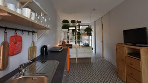 A modern kitchen with a built-in sink, wooden cabinets, and a TV on a wooden stand. - Apartment in Ieper With Terrace (Ypres)