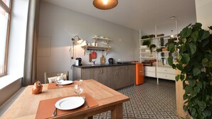 A modern kitchen with wooden cabinets, a dining table with a placemat, and a hanging light fixture. - Apartment in Ieper With Terrace (Ypres)