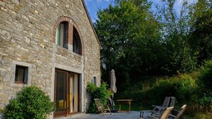 A stone building with a patio area featuring outdoor seating and a table. - Chimay Nature Hideaway (Chimay)