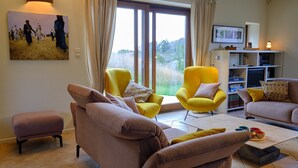 A living room with a sofa, armchairs, a coffee table, and a bookshelf. - Chimay Nature Hideaway (Chimay)