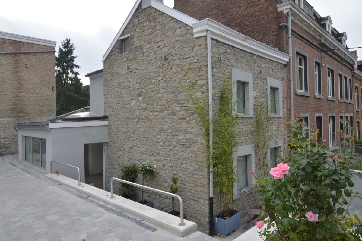 A stone building with a modern design, featuring a metal railing and potted plants.