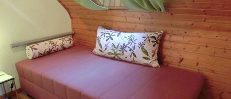 Ein gemütliches Zimmer mit Holzbalkendecke, einem rosafarbenen Sofa und Kissen mit Blumenmuster.
