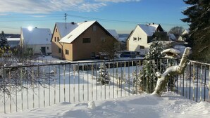 Asuinalue, jossa on taloja, lumipeitteinen aita ja kirkas taivas.