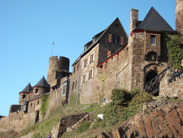 A historic stone building with multiple towers and a steeply sloped roof.
