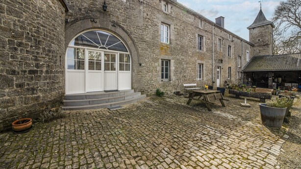 Un bâtiment en pierre doté d’une grande fenêtre en arc de cercle et d’une petite tour.