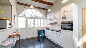 Une cuisine moderne avec des meubles blancs, un sol carrelé noir et une grande fenêtre.