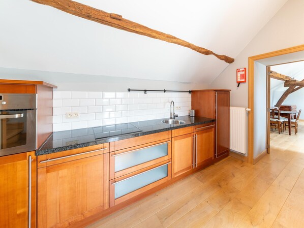 Une cuisine moderne avec des meubles en bois, un évier en acier inoxydable et un plan de travail noir.