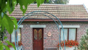 Una casa de ladrillo con techo de tejas, una puerta de madera y un banco en el exterior.