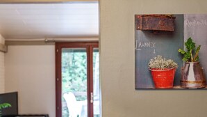 Una habitación con una mesa de madera, un televisor y una pizarra con plantas en macetas.