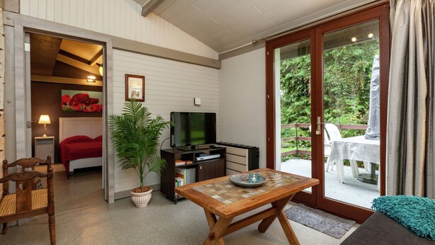 Una sala de estar acogedora con televisor, una mesa de madera y una planta en maceta.