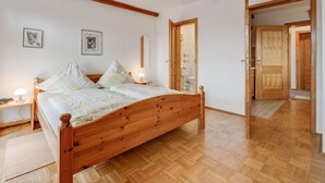 Ein Schlafzimmer mit einem hölzernen Bett, zwei Nachttischen mit Lampen, einem Holzschrank und einer Tür zum Badezimmer.