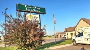 A Country Club Inn & Suites sign, a building, and a delivery truck.