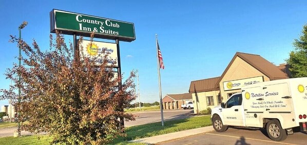 A Country Club Inn & Suites sign, a building, and a delivery truck.
