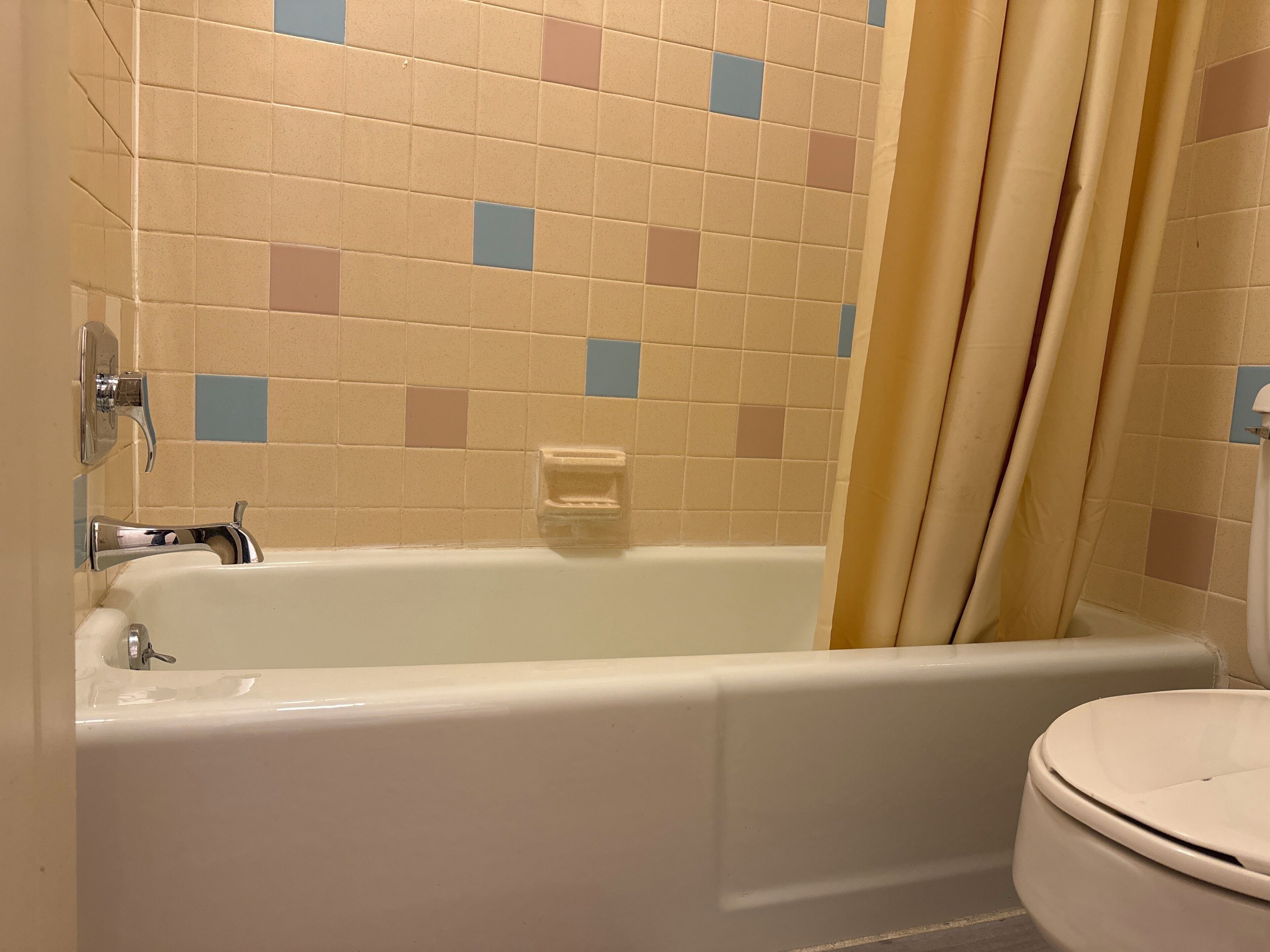 Une salle de bain avec une baignoire, des toilettes et des murs carrelés.