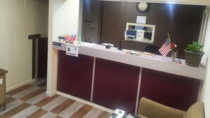 A reception desk with a computer, a clock, and a small American flag.