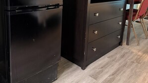 A compact kitchenette with a microwave, refrigerator, and a flat-screen TV on a wooden cabinet.