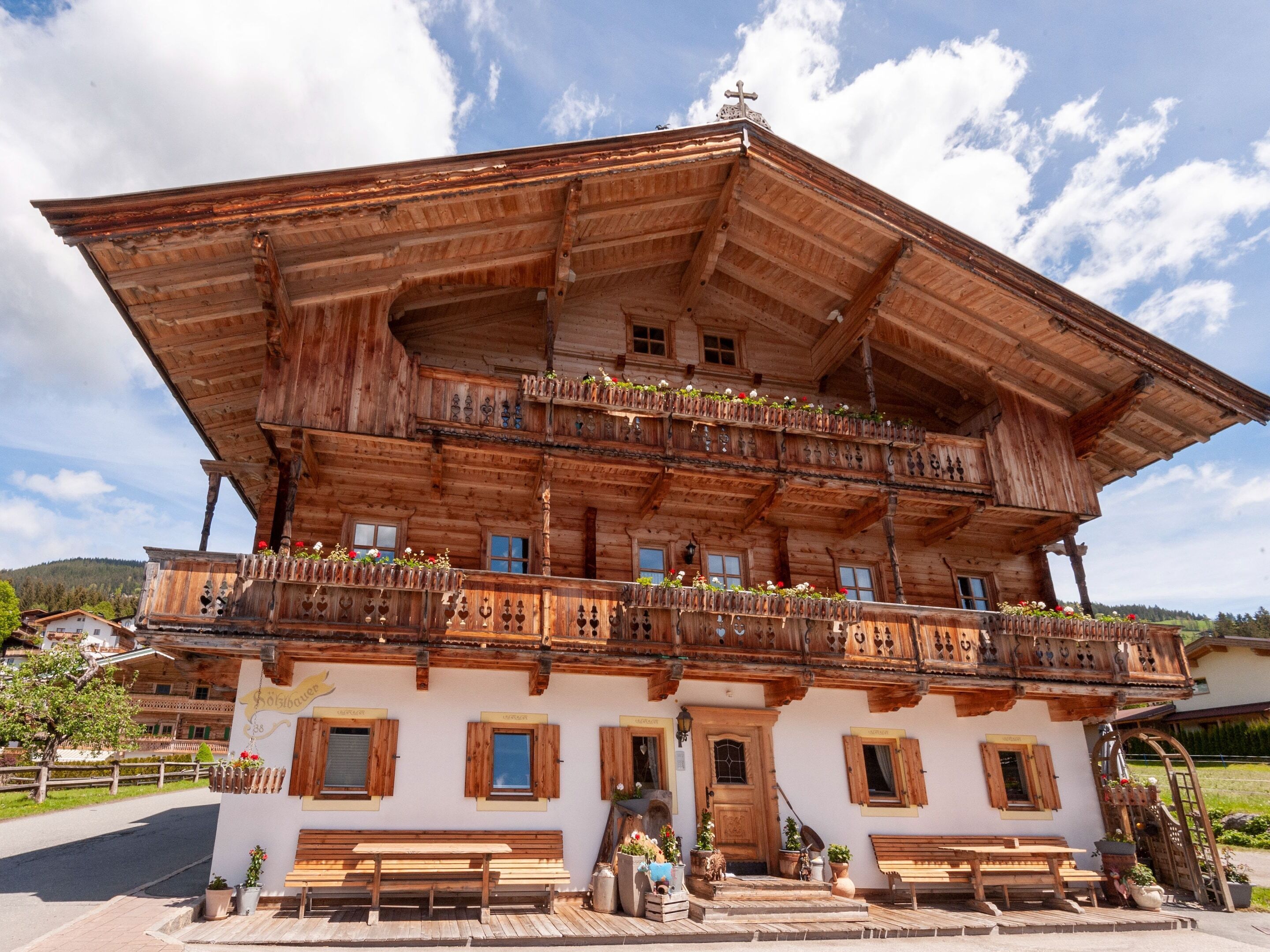 Eine traditionelle Holzhütte mit mehreren Balkonen, einem Hauseingang und Sitzgelegenheiten im Freien.