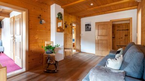 A cozy wooden interior with a sofa, a rocking horse, and a small table with a plant. - Beautiful Flat in Kirchberg Near the ski Area (Kirchberg in Tirol)