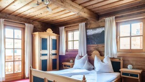 A wooden bedroom with a large bed, a wardrobe, and a nightstand. - Beautiful Flat in Kirchberg Near the ski Area (Kirchberg in Tirol)