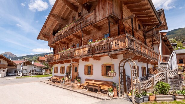 A traditional wooden chalet with multiple balconies, outdoor seating, and a staircase leading to the upper floors. - Beautiful Flat in Kirchberg Near the ski Area (Kirchberg in Tirol)