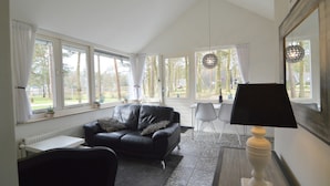 A modern living room with a black leather sofa, a white radiator, and a table lamp. - Holiday Home in Stramproy Near Nature Reserves (Stramproy)
