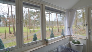 A room with large windows, a radiator, and a small potted plant on the windowsill. - Holiday Home in Stramproy Near Nature Reserves (Stramproy)