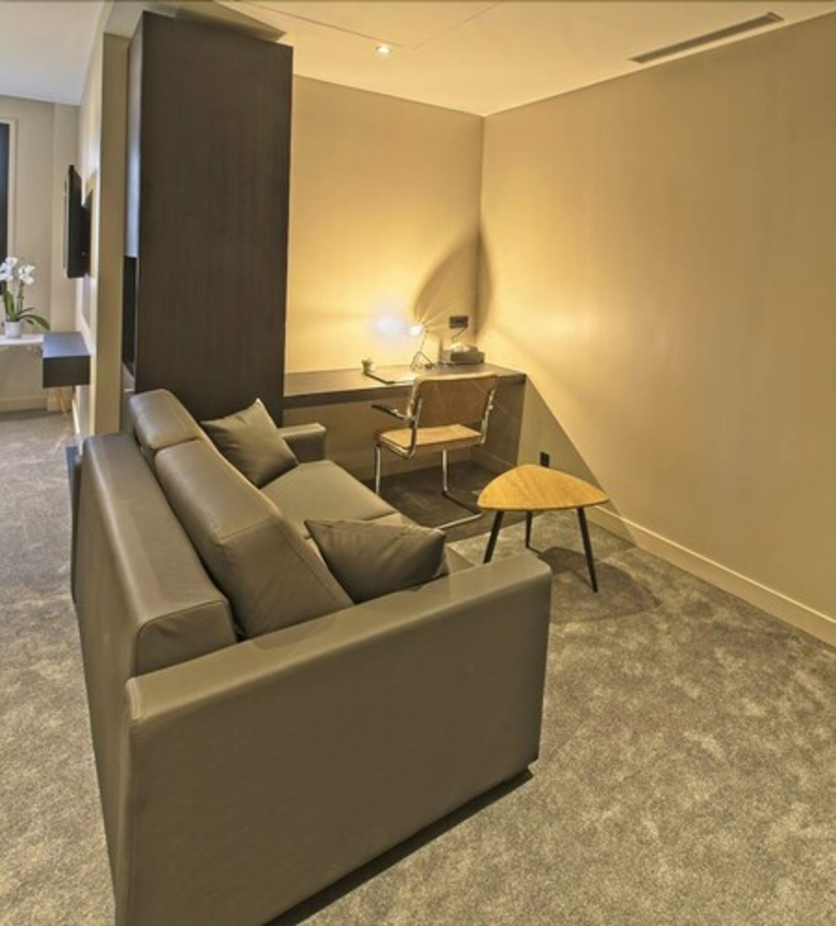Un salon moderne avec un canapé d’angle, une petite table et un fauteuil.