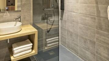 A modern bathroom with a glass-enclosed shower, a wooden vanity, and a large mirror.