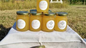 A picnic setup with jars of honey on a blanket in a grassy field.