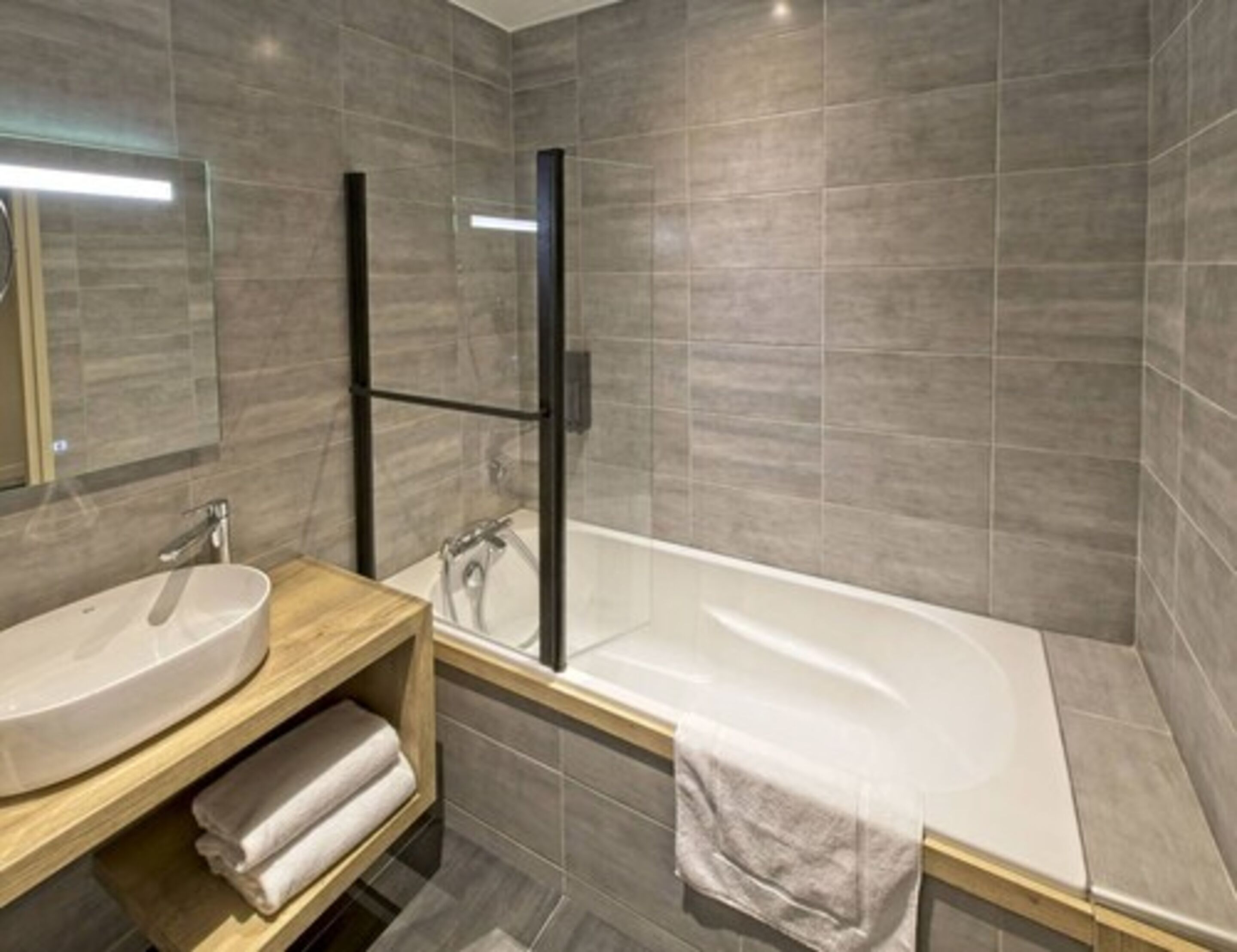 Un baño moderno con una bañera independiente, un tocador con lavabo y un box de ducha de vidrio.