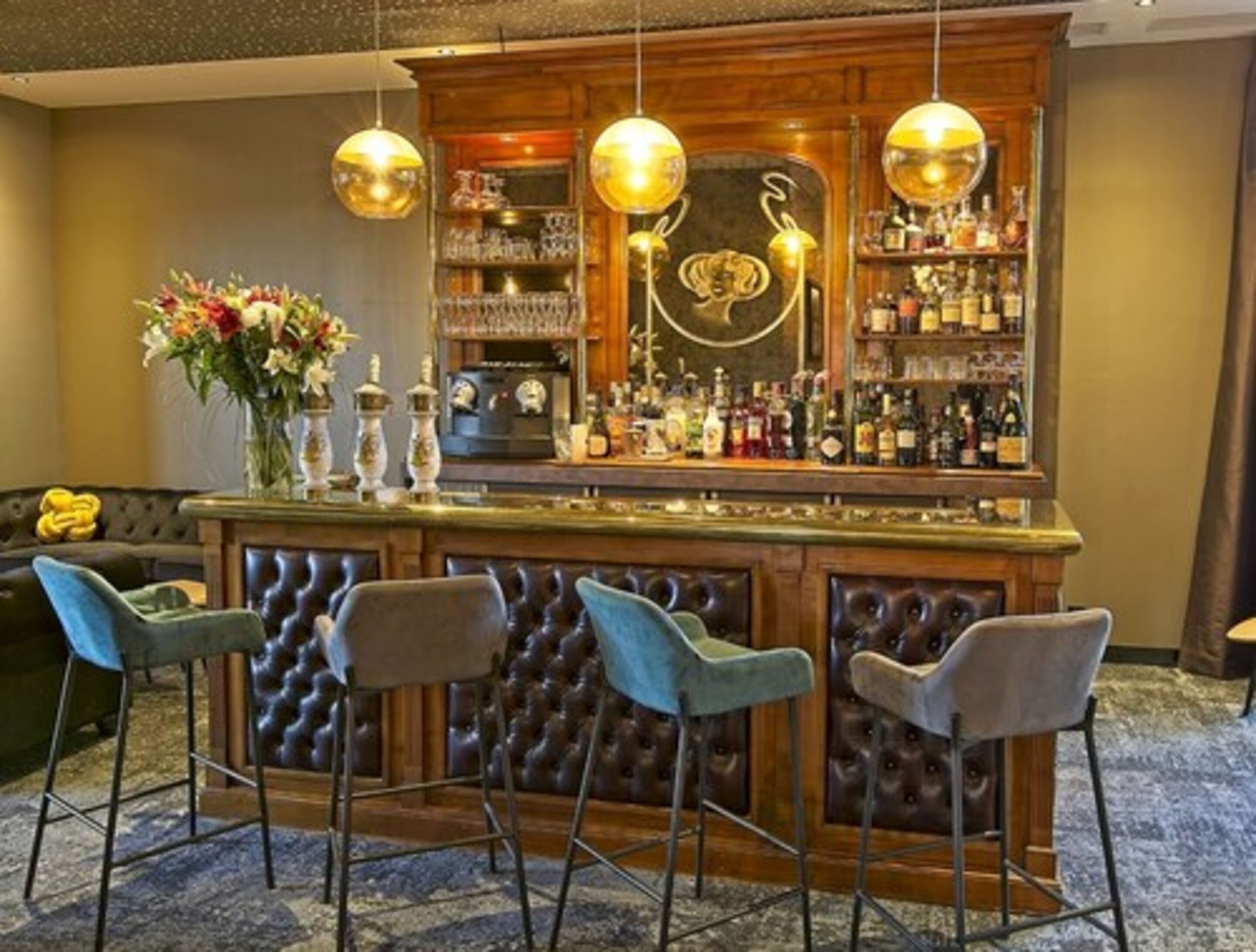 A bar area with a wooden counter, bar stools, and hanging pendant lights.