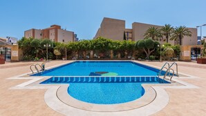 Ein Pool mit geometrischem Design, umgeben von einer gefliesten Terrasse und Palmen.