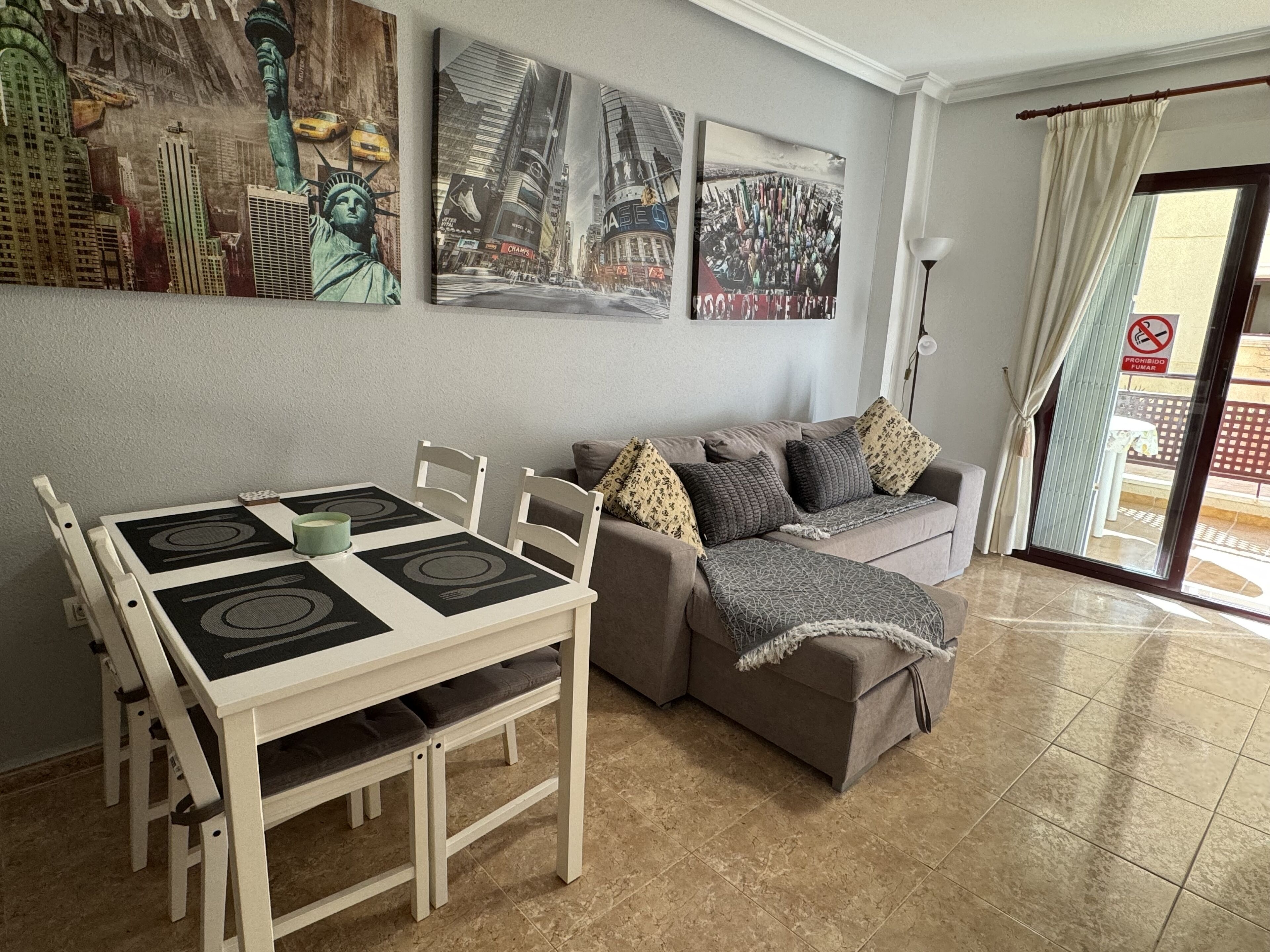 A living room with a dining table, sofa, and artwork on the walls.
