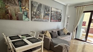 Ein Wohnzimmer mit Esstisch, Sofa und Kunstwerken an den Wänden.