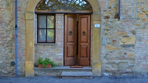 A stone building with a wooden door and a window. - Agriturismo Le Case di San Vivaldo (Montaione)